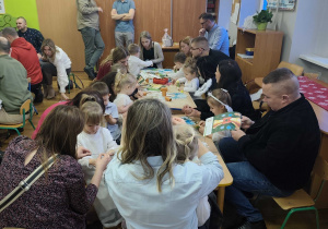 Rodzice z dziećmi wykonują świąteczne ozdoby