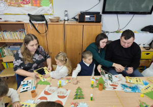 Rodzice z dziećmi wykonują świąteczne ozdoby