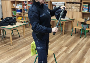 Pani policjantka prezentuje dzieciom akcesoria policyjne