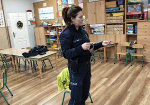 Pani policjantka prezentuje dzieciom akcesoria policyjne