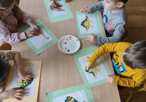 Dzieci wyklejają dinozaury plasteliną