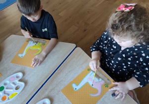 Dzieci kolorują dinozaury farbami