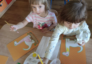 Dzieci kolorują dinozaury farbami