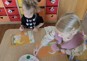 Dzieci kolorują dinozaury farbami