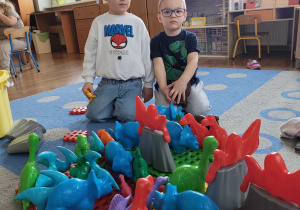 Chłopcy prezentują swoją wyspę dinozaurów z klocków