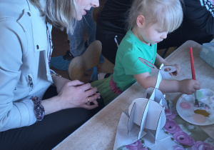 Dzieci z rodzicami robią wielkanocne ozdoby