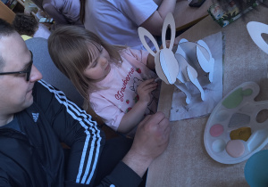 Dzieci z rodzicami robią wielkanocne ozdoby