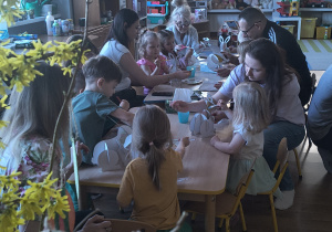 Dzieci z rodzicami robią wielkanocne ozdoby