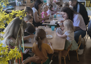 Dzieci z rodzicami robią wielkanocne ozdoby