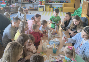 Dzieci z rodzicami robią wielkanocne ozdoby