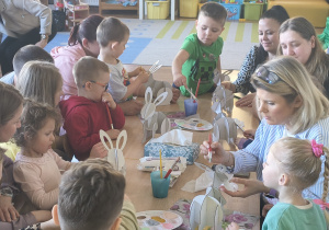 Dzieci z rodzicami robią wielkanocne ozdoby