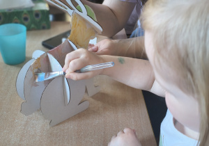 Dzieci z rodzicami robią wielkanocne ozdoby