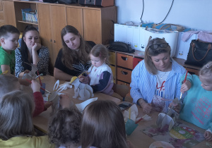 Dzieci z rodzicami robią wielkanocne ozdoby