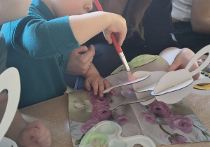 Dzieci z rodzicami robią wielkanocne ozdoby