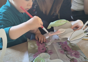 Dzieci z rodzicami robią wielkanocne ozdoby