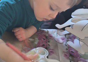 Dzieci z rodzicami robią wielkanocne ozdoby