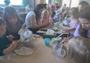 Dzieci z rodzicami robią wielkanocne ozdoby