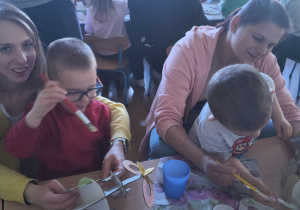 Dzieci z rodzicami robią wielkanocne ozdoby