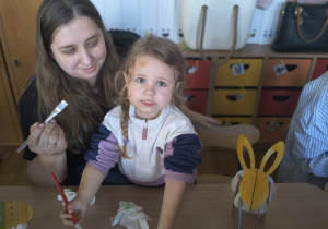 Dzieci z rodzicami robią wielkanocne ozdoby