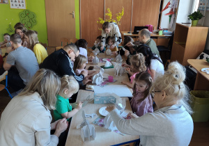 Dzieci z rodzicami robią wielkanocne ozdoby