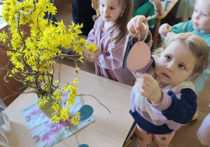 dzieci wieszają jajeczka na drzewku