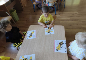 Dzieci układają puzzle z wizerunkiem pszczoły