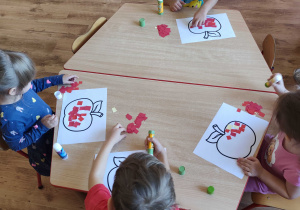 Dzieci wykonują prace plastyczną przy stolikach