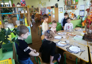 Chłopcy pomagają dziewczynkom usiąść do stołu.