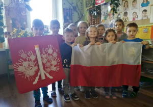 Dzieci trzymają przed sobą godło i flage naszego kraju.