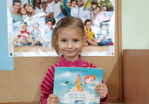 Marysia trzyma książeczkę pt.: Wróżka Zuzia i cudowne dzieci" autorstwa M. Kryger poruszającą tematykę niepełnosprawności dzieci