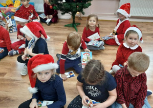 Dzieci siedzą na podłodze ze swoimi prezentami