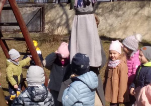 Dzieci stoją koło marzanny i żegnają zimę