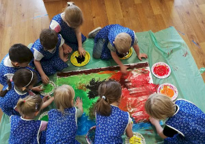 Dzieci na brystolu metodą "Malowania Dziesięcioma Palcami" malują kolory ziemi.