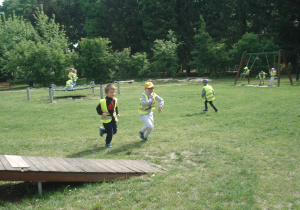 troje dzieci biegnie po trawie