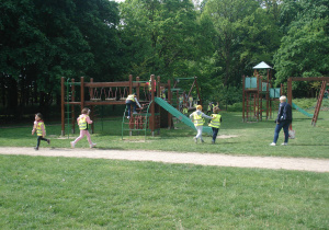 dzieci biegają, a jedno dziecko się wspina na urzadzenie terenowe