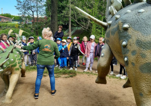 Pani przewodnik opowiada dzieciom o zwyczajach dinozaurów