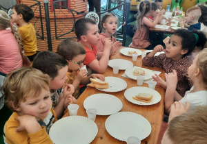 Dzieci jedzą posiłek przy wspólnym stole
