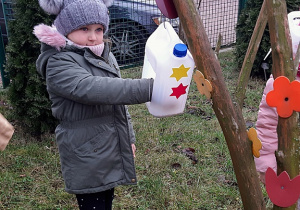 Nikola wsypuje ziarna do karmnika.