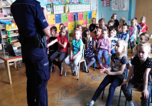 Policjantka stoi przed siedzącymi dziećmi