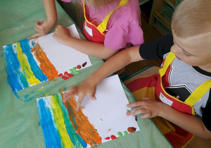 Ala i Antoś malują palcami kolorowe tło.