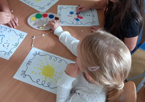 Dzieci przy stoliku malują obrazki z elementem kropki