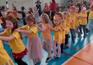 Dzieci ustawione w pociąg tańczą w rytm piosenki