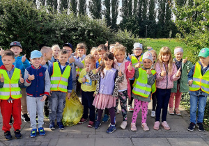 Dzieci stojące w grupie są zadowolone z efektów sprzątania parku.