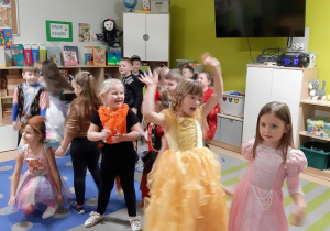 Dzieci przebrane w bajkowe stroje tańczą w rytm muzyki.
