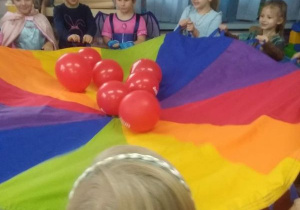 Zabawa z chustą animacyjną. Dzieci próbują utrzymać na chuście balony.