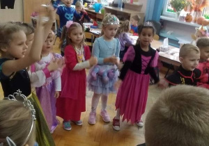 Dzieci stoją w kole, śpiewają piosenkę, ilustrując ją ruchem