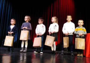 dzieci stoją na scenie z odebranymi nagrodami