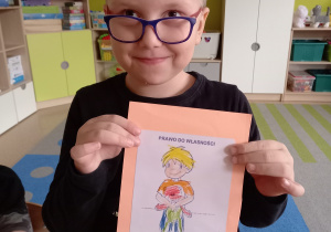Piotruś trzyma w ręku ilustrację przedstawiającą prawo dziecka do własności