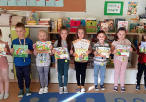 Dzieci stoją i trzymają w rękach nagrody książkowe za udział w konkursie