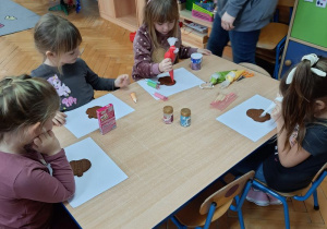 Dziewczynki dekorują piernikowe Mikołaje